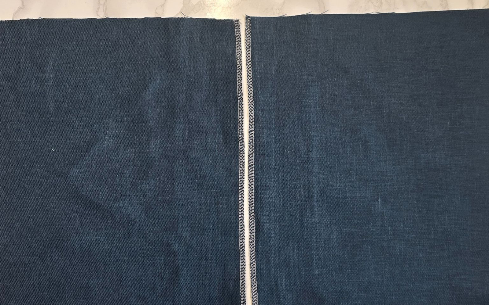 Blauwe stof randen overlocked met wit garen