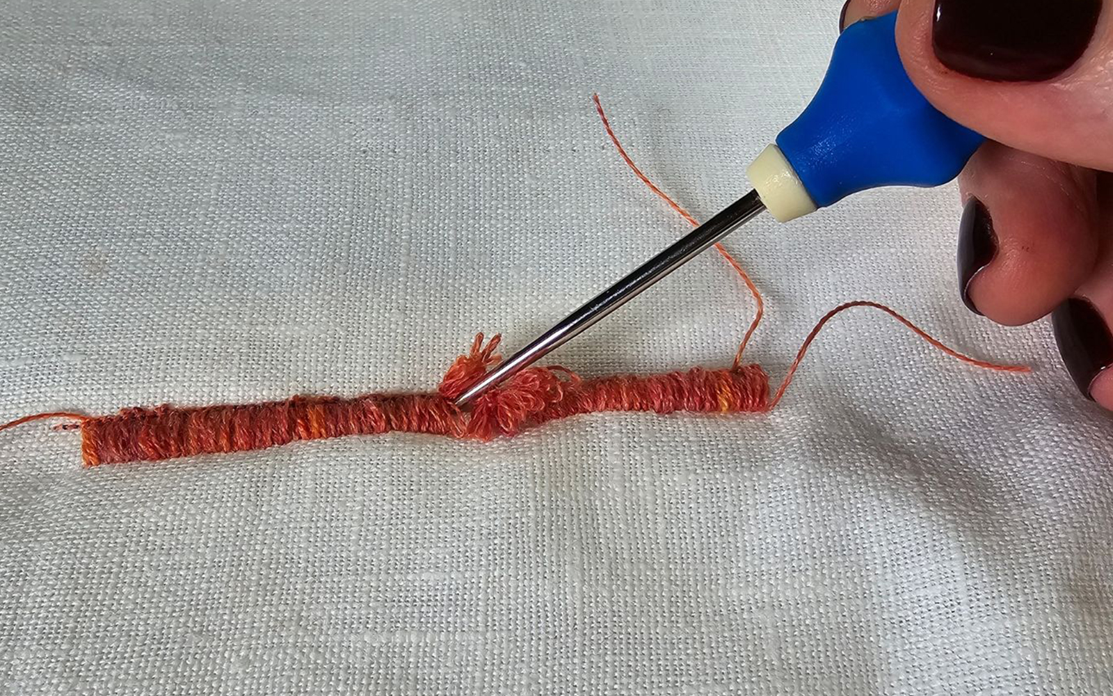 Awl teasing loops through fabric to the right side