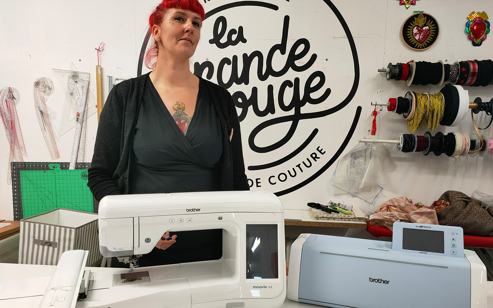 Een roodharige vrouw staat achter een naaimachine