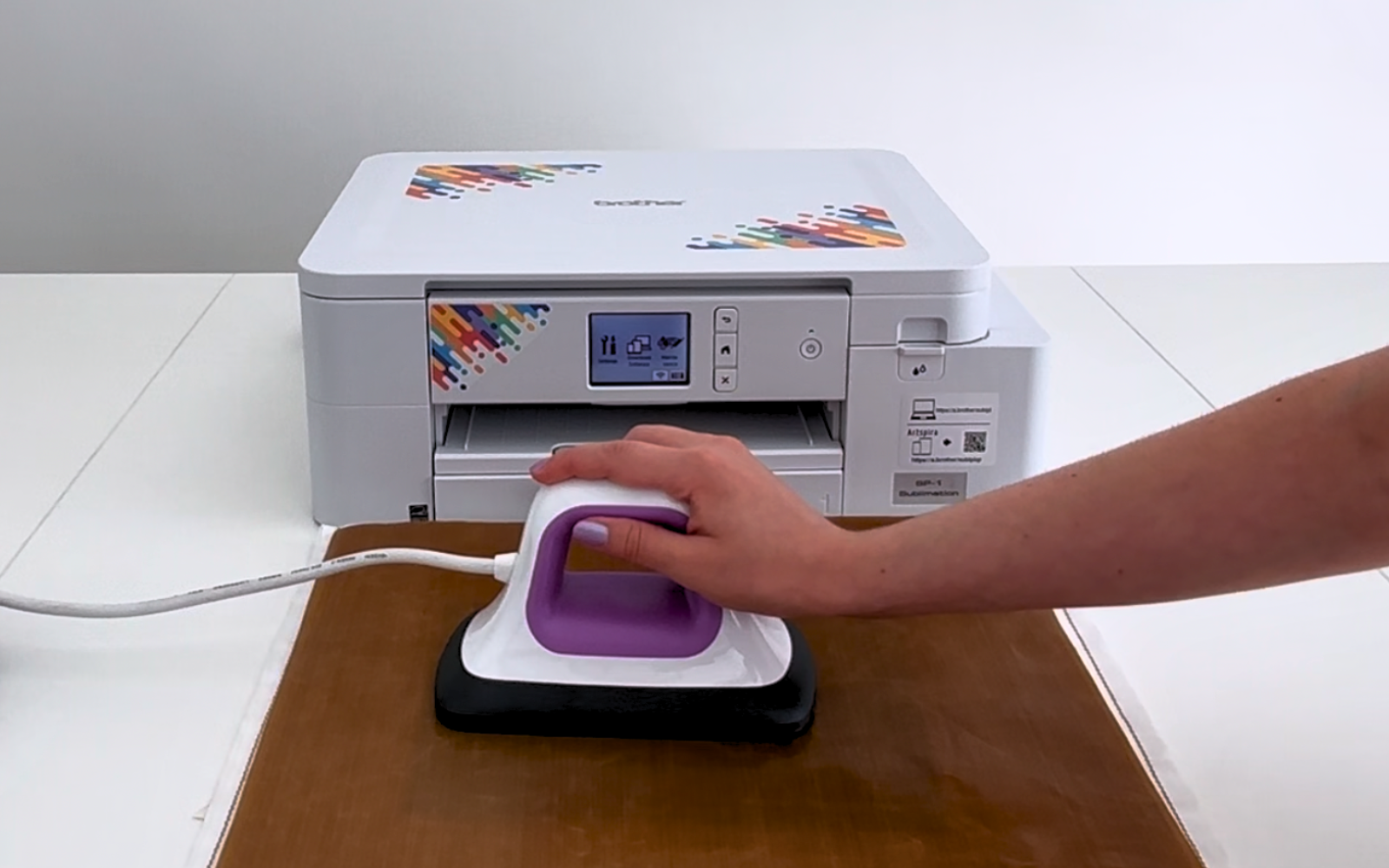 Hand presses a heat press on a heatproof sheet