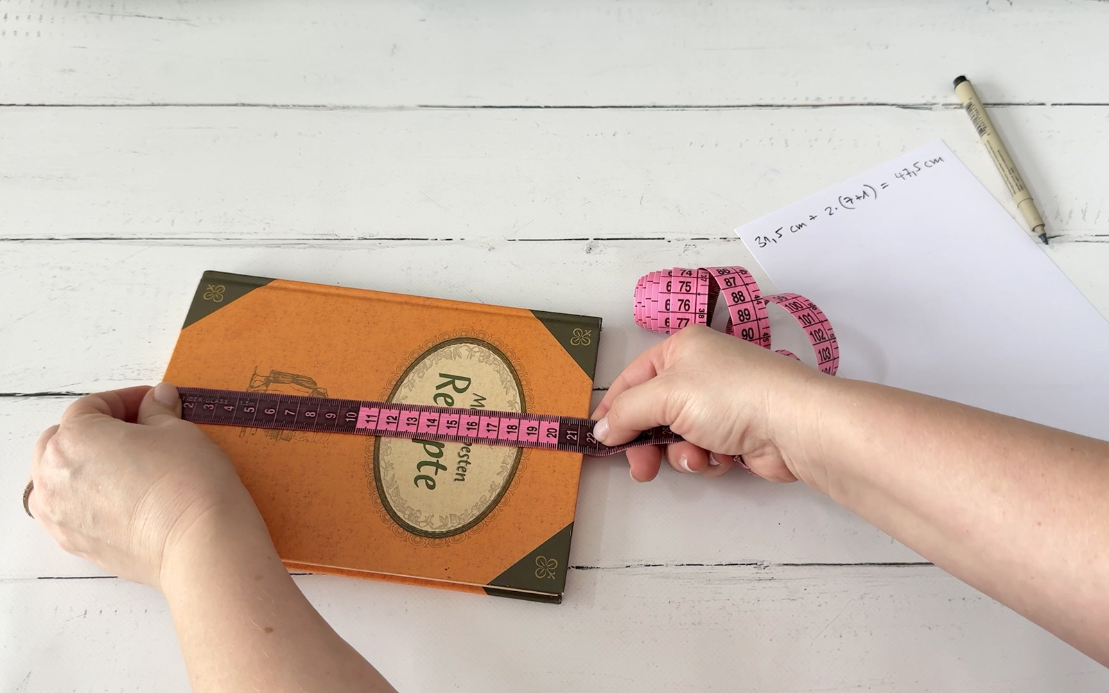Hands measuring height of book