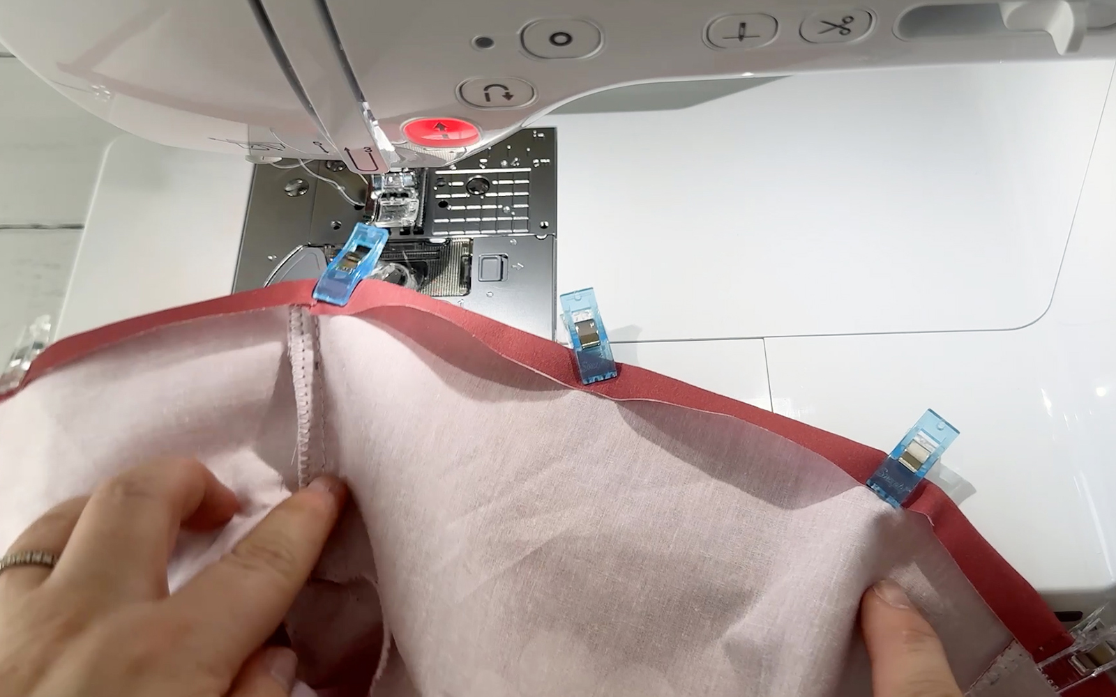 Clips holding the hem in place on doll’s hoodie