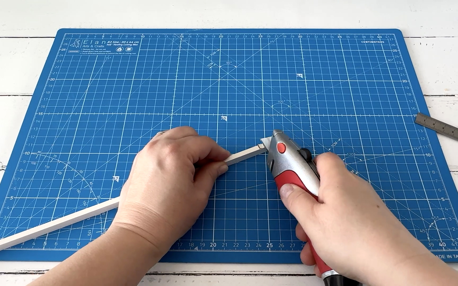cutting small notches in a wooden stick using a craft knife