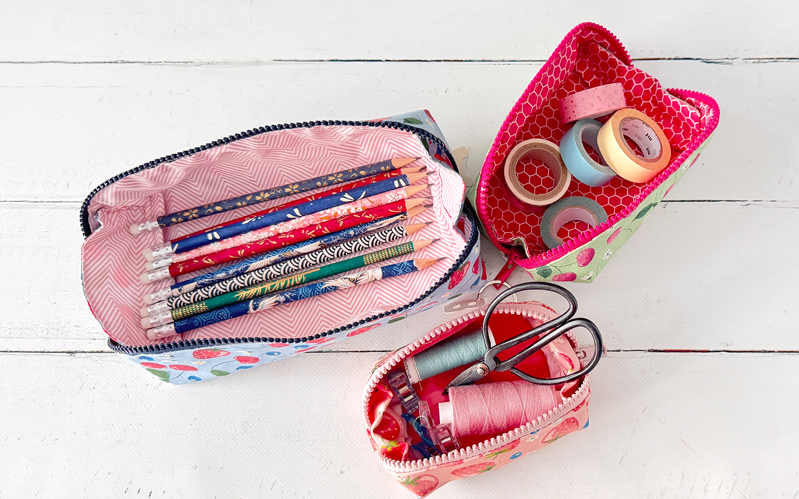 Three pencil cases opened with supplies in them.