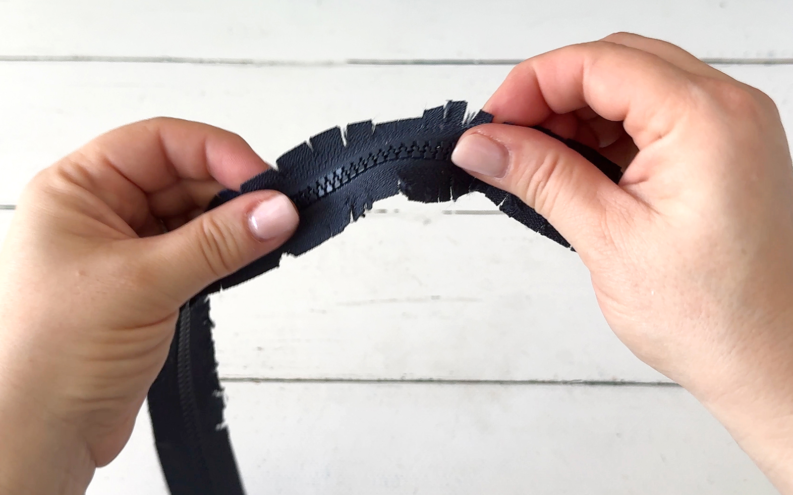 hands holding zipper with tape snipped.
