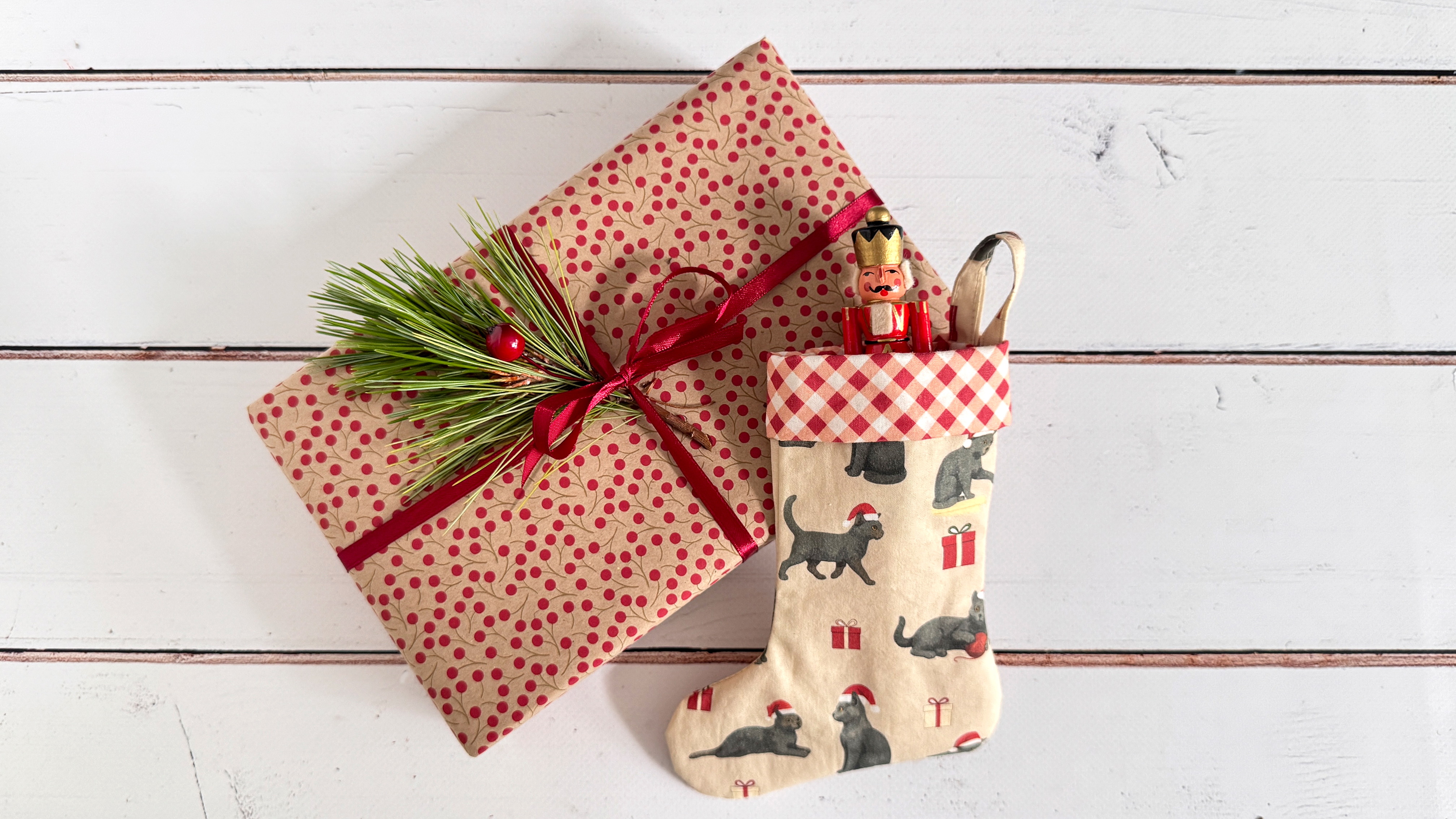 Printed stocking and wrapped Christmas gift on white wood