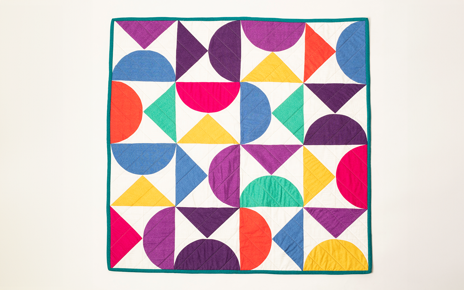 quilt géométrique créé à partir de blocs violets, rouges, verts et bleus