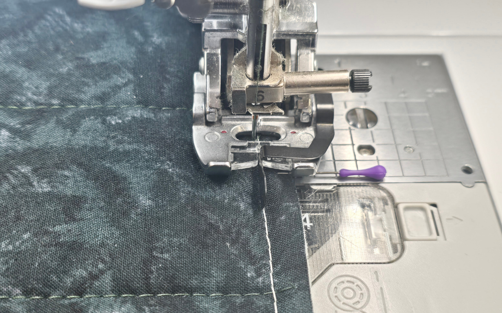 Pied-de-biche Brother pour piqûre dans la couture sur tissu vert.