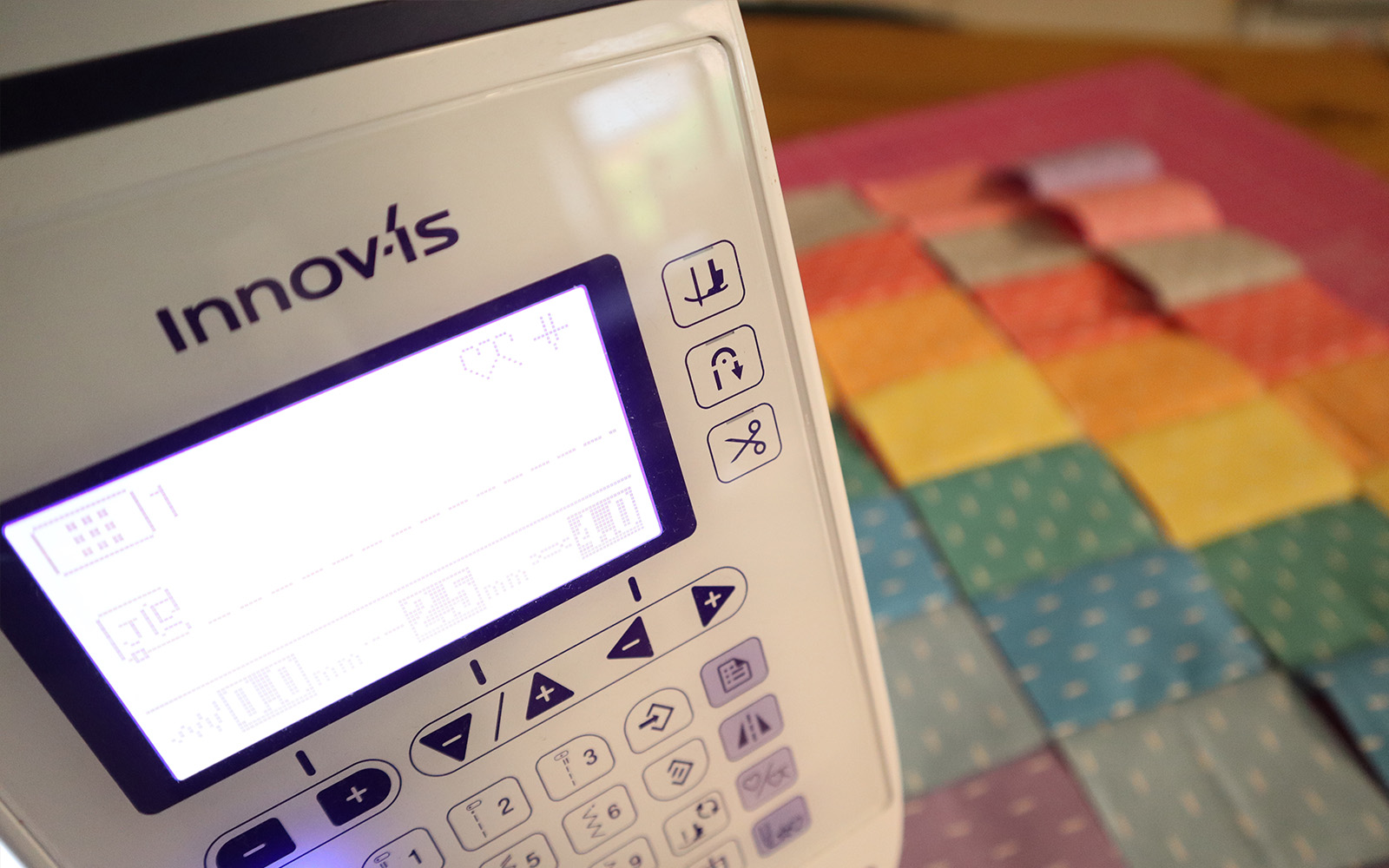 Screen of sewing machine with sewn fabric strips in background