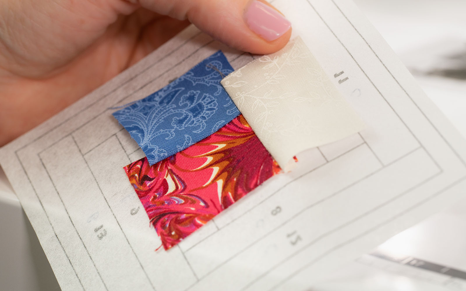 hand holding paper with numbered pattern and quilted fabric