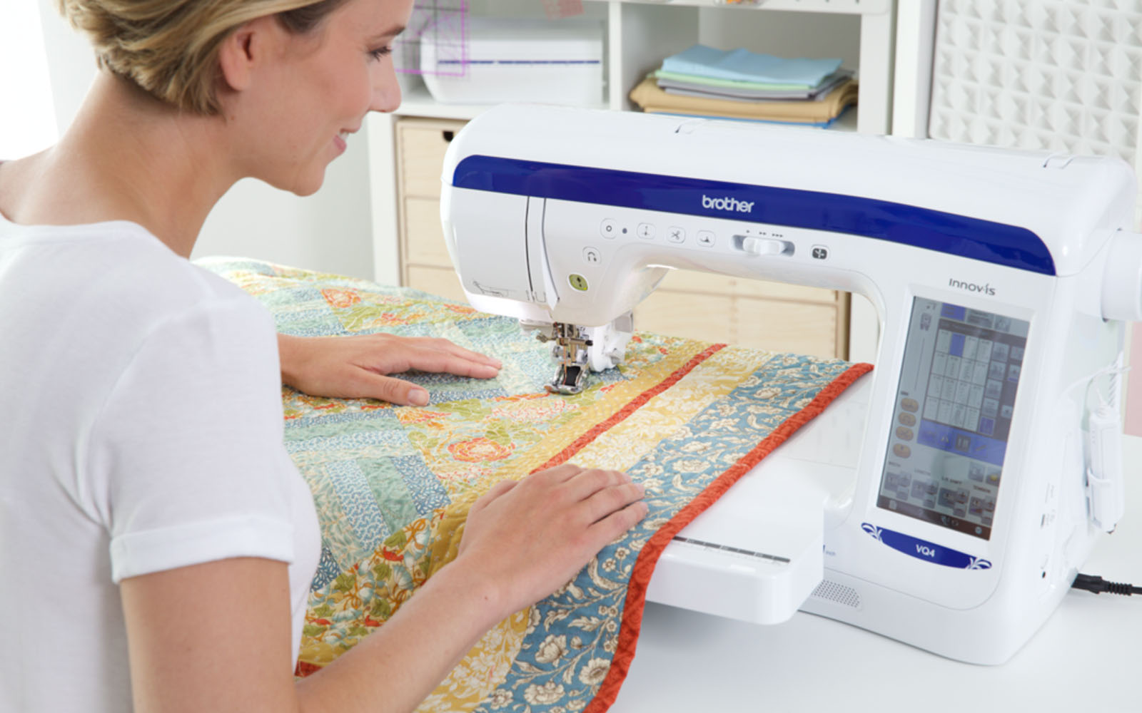 blonde haired woman quilting yellow floral quilt on Brother Innov-is VQ4