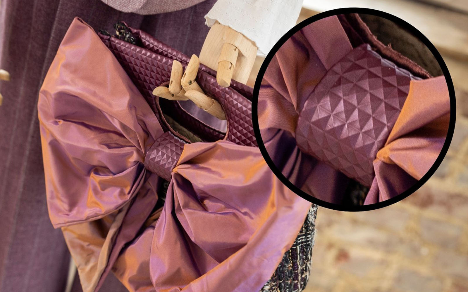 Close up of vinyl band holding bow on purple handbag