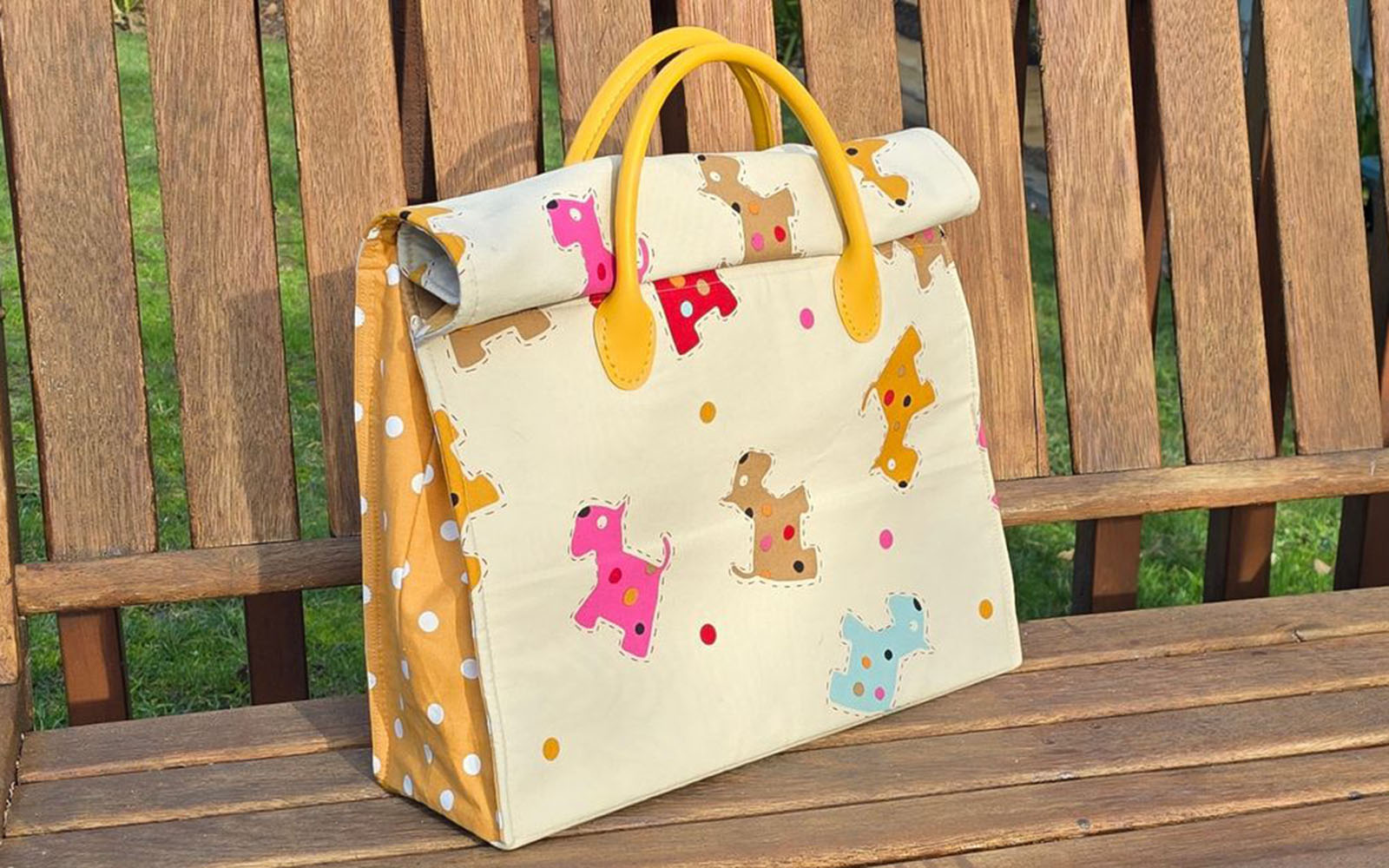 Dog and polkadot tote bag with yellow handles on wooden bench