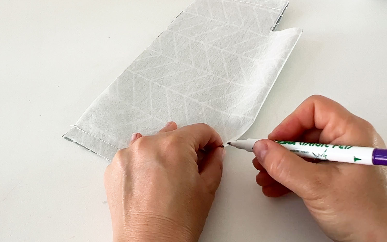 Hands marking fabric with pen