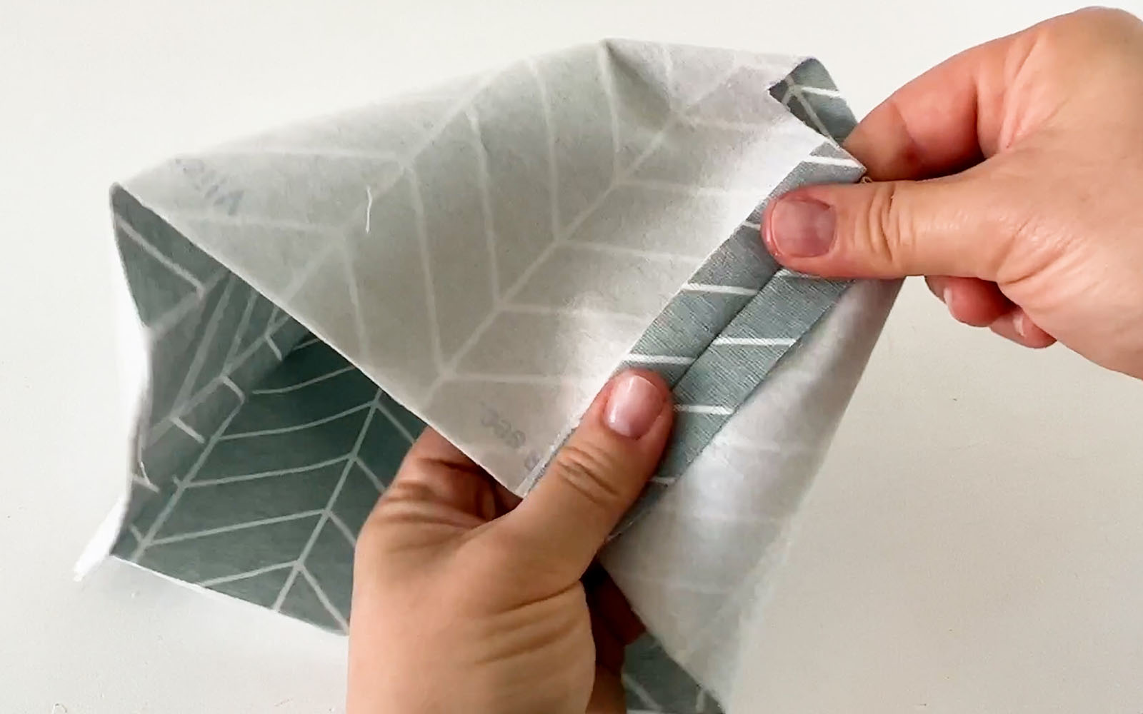 Seam on grey fabric pressed open with fingers