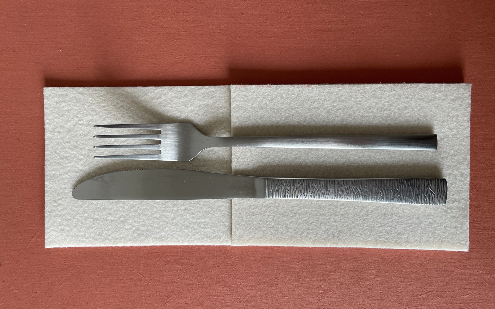 silver knife and fork on white napkin