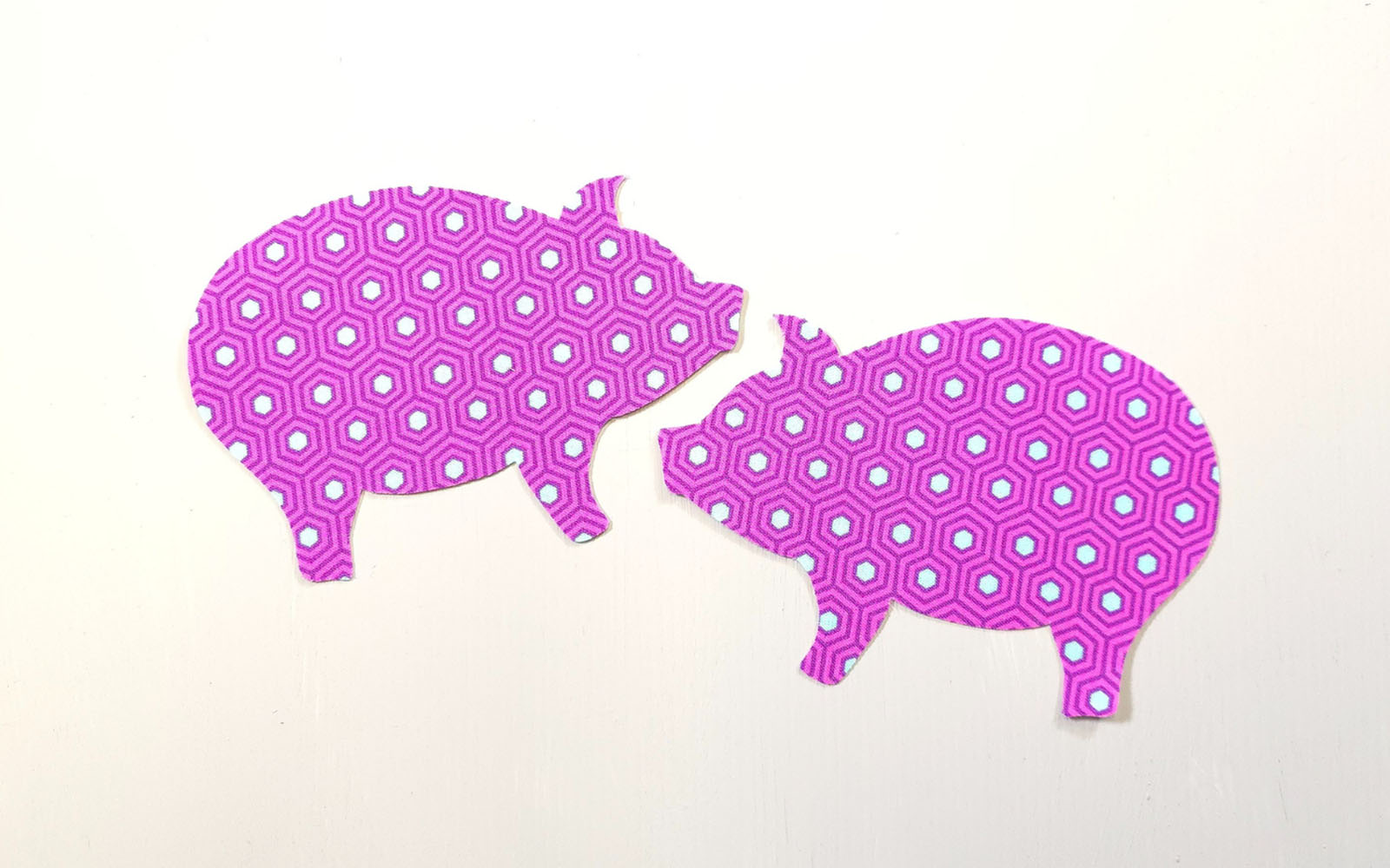 Pink pig shaped fabric pieces on white background