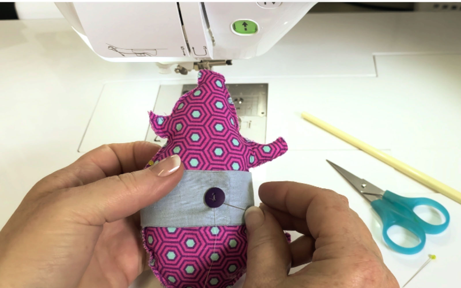 Hand sewing button to pink fabric Glücksschwein pig