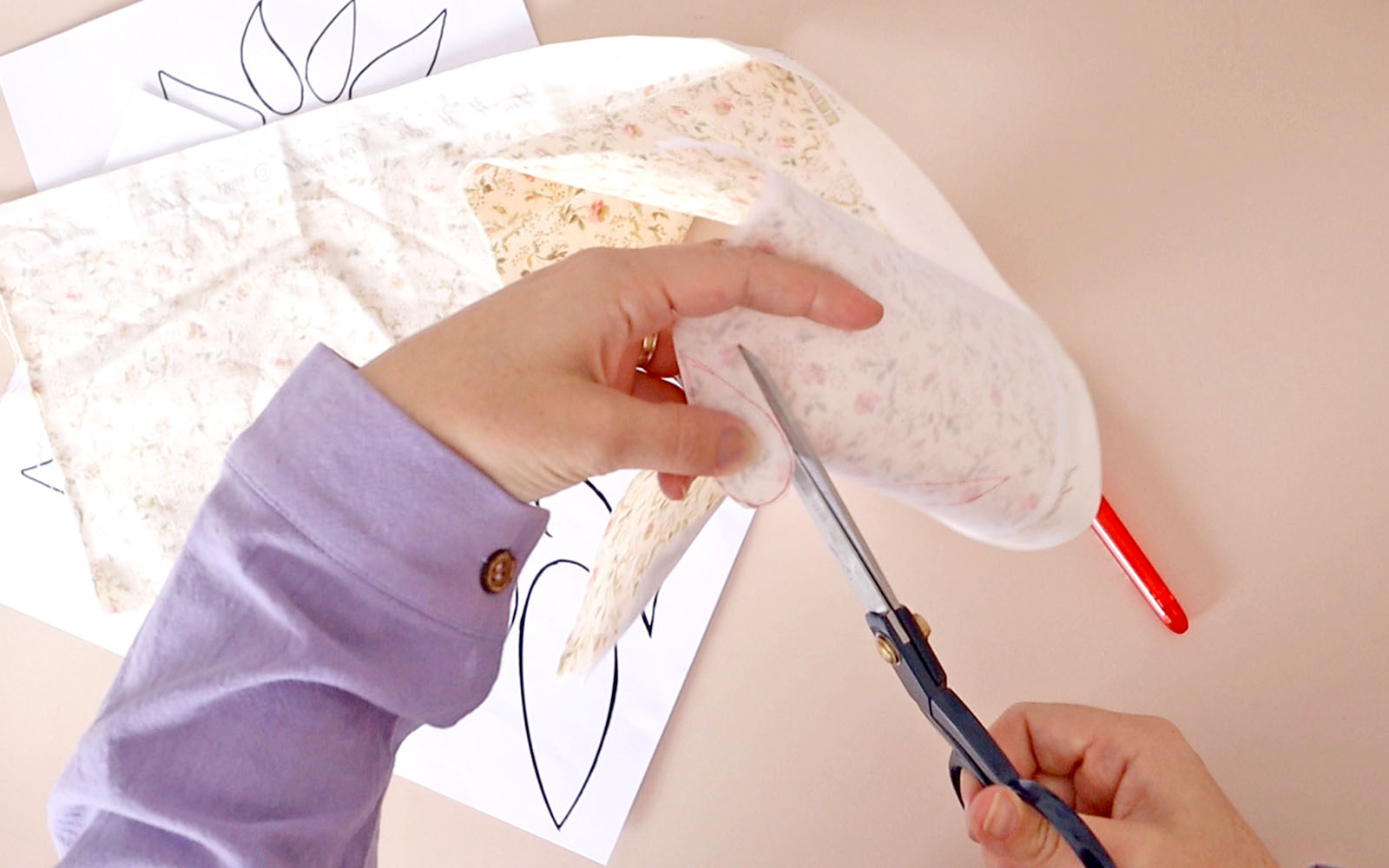 Hands cutting petal shapes from cream fabric