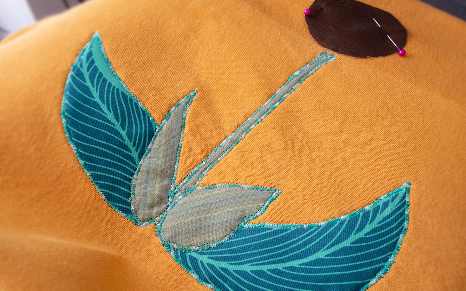 Fabric leaves and stem sewn to yellow background