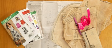 Sewing patterns and tape measure on wooden background