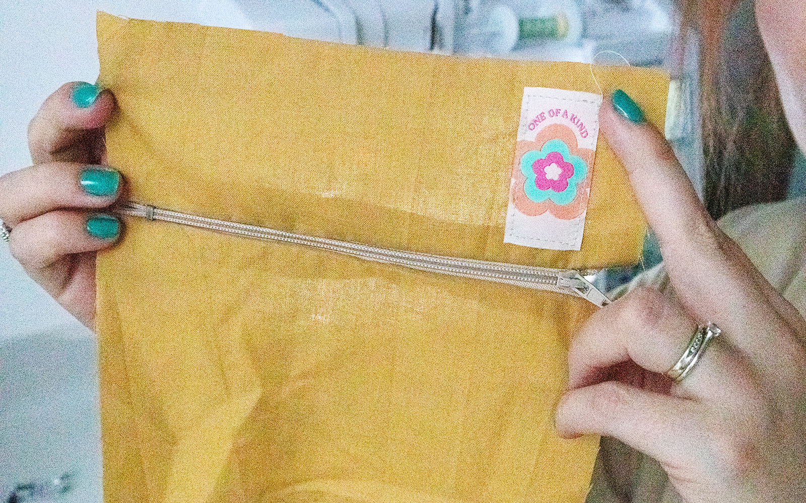 Hands holding mustard fabric with zip sewn in