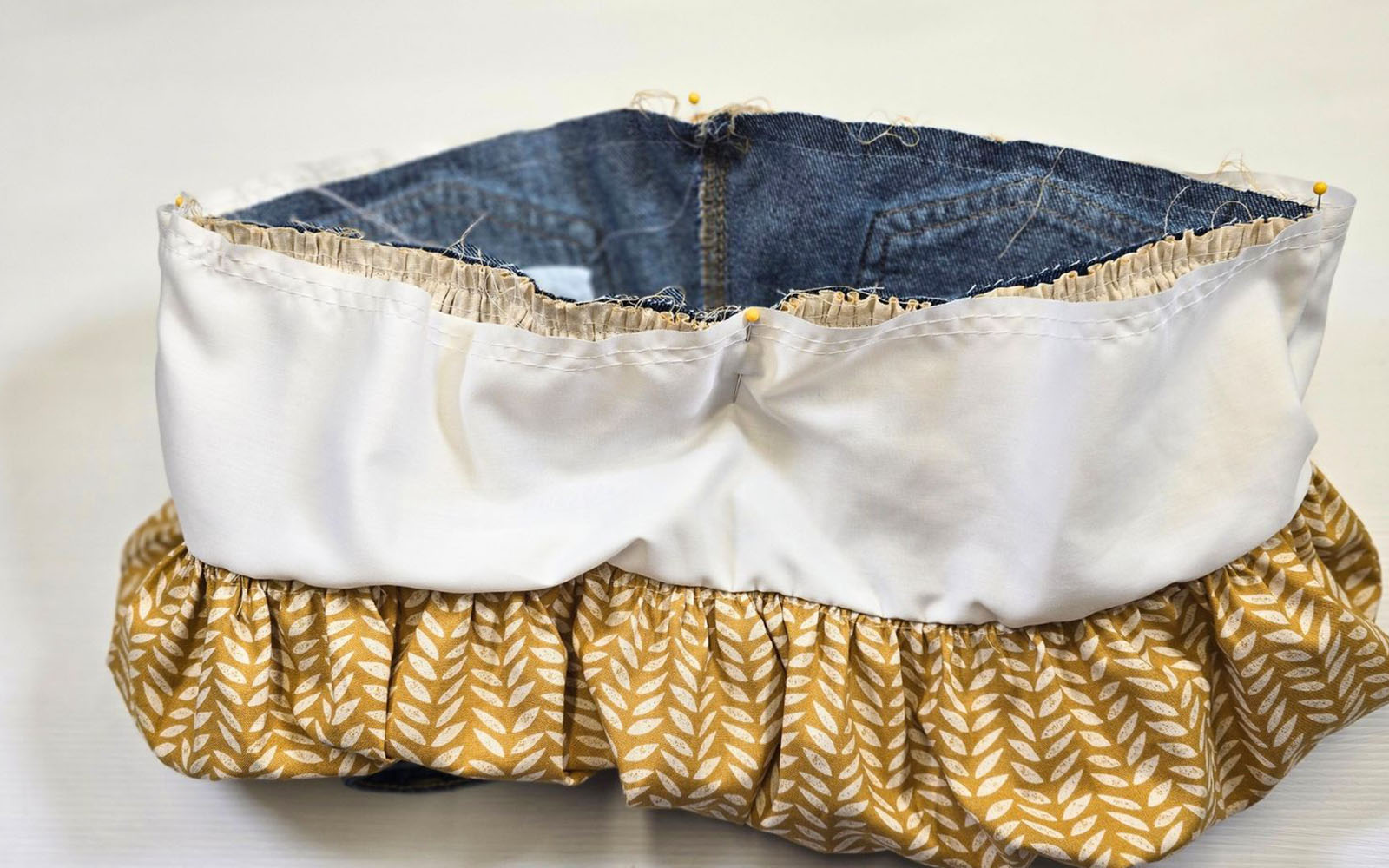 Ruffled yellow fabric and cut jeans on white background