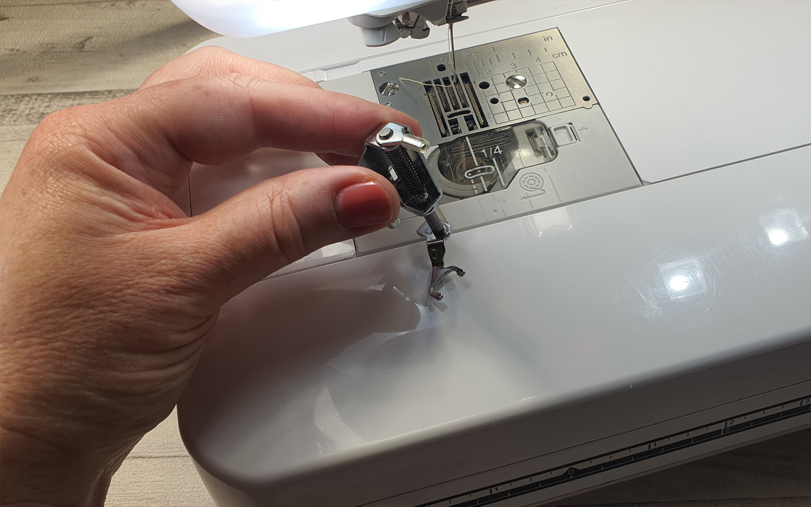 sewing foot in hand in front of sewing machine