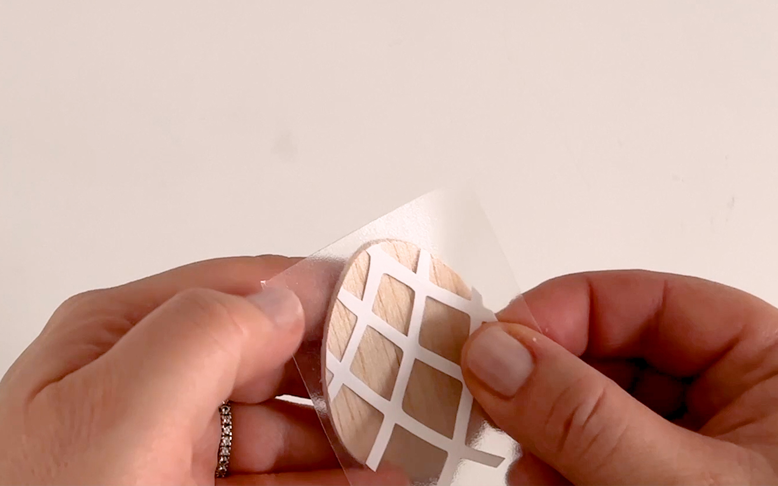 hand holding small balsa wood egg and attaching vinyl sticker