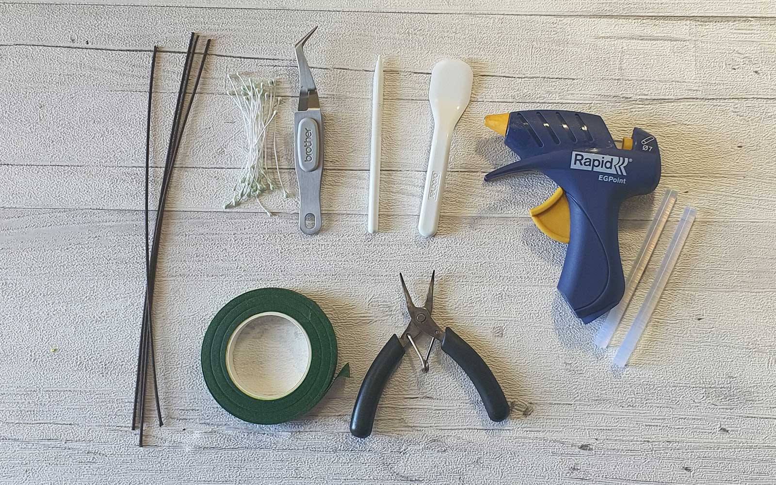 Papercraft cutting and gluing tools on white wooden background