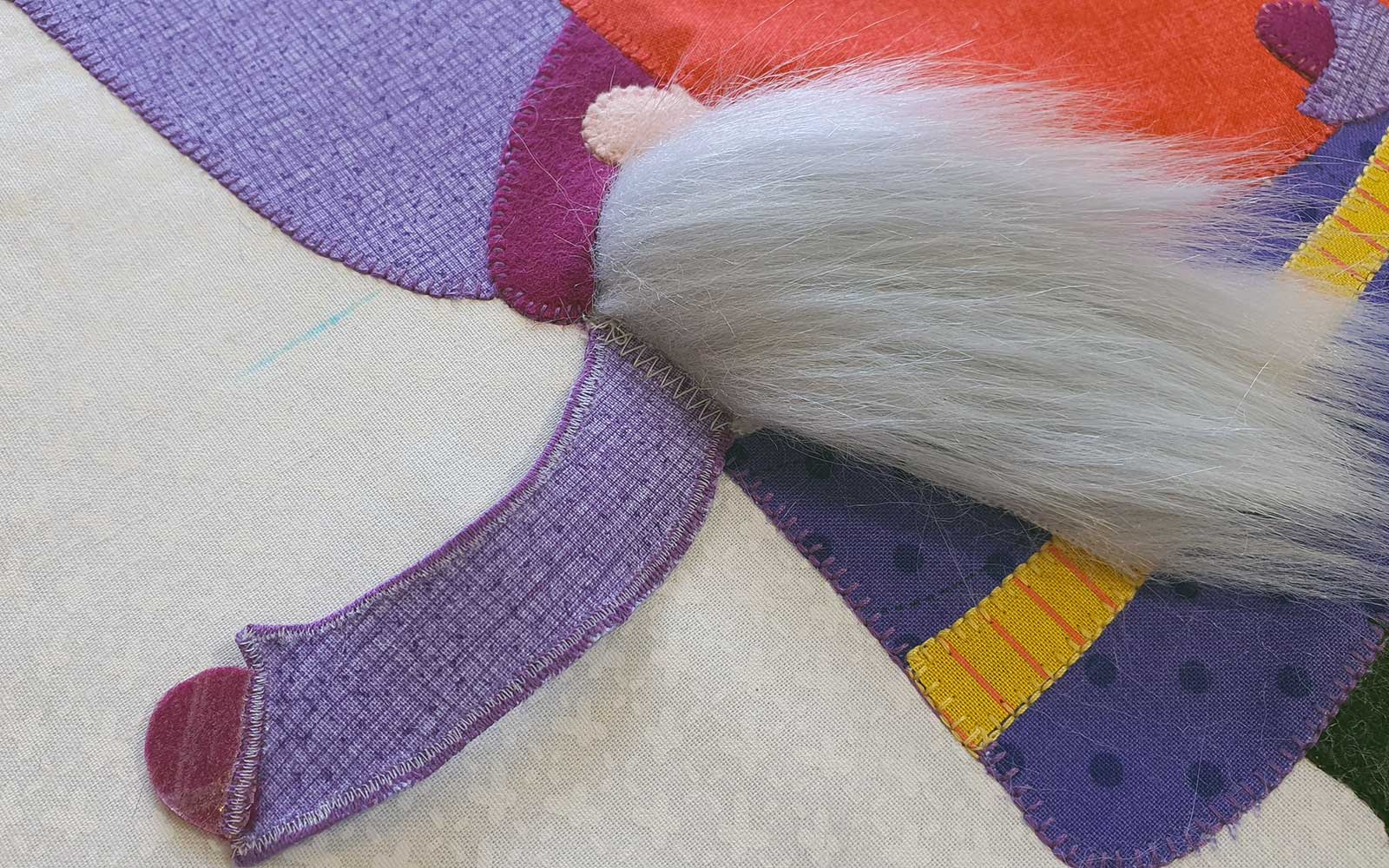 Braccio viola dello gnomo su tessuto bianco