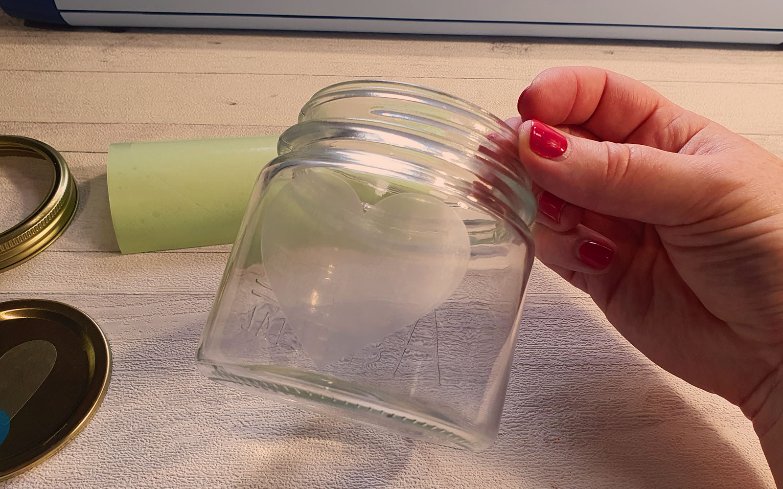 Hand hält Glas mit Herzschablone in der Hand