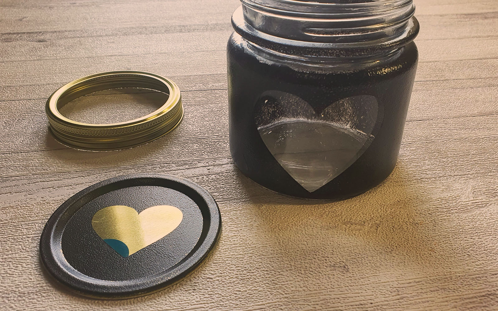 vasetto dipinto di nero con spioncino a forma di cuore e coperchio a fianco