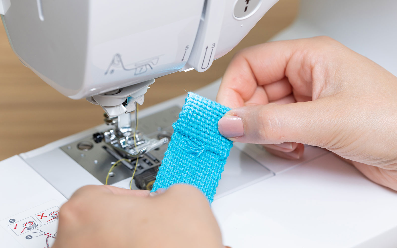 sewing end of blue ribbon on sewing machine