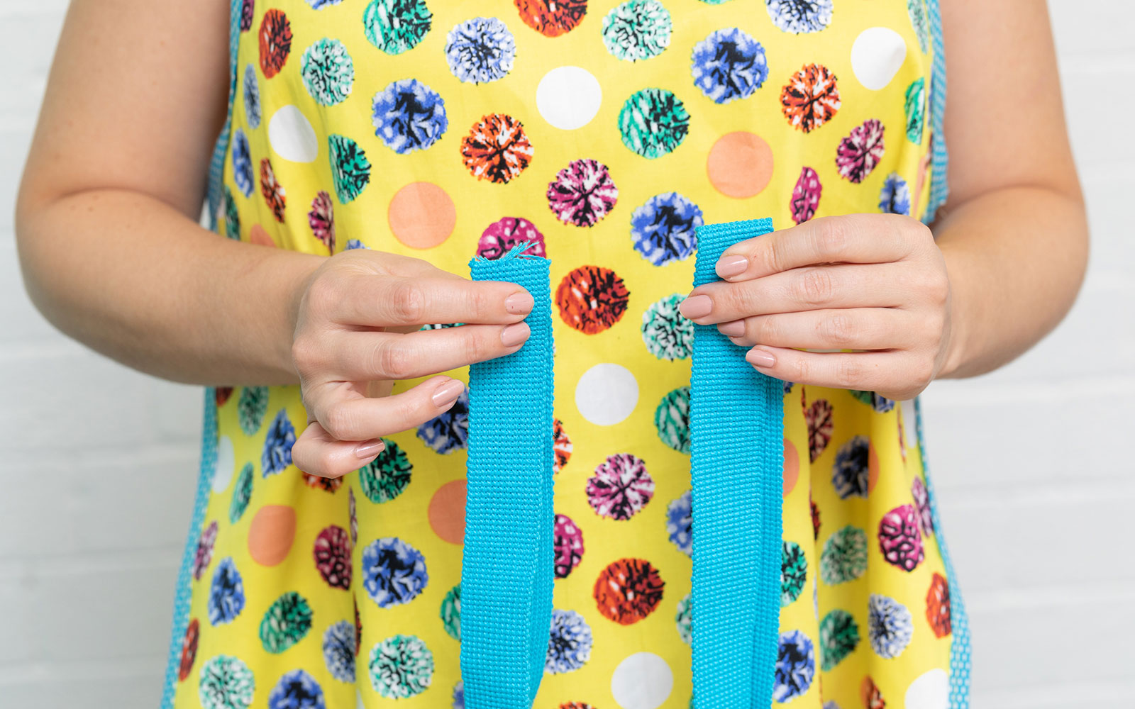 woman wearing yellow apron measuring ties round waist
