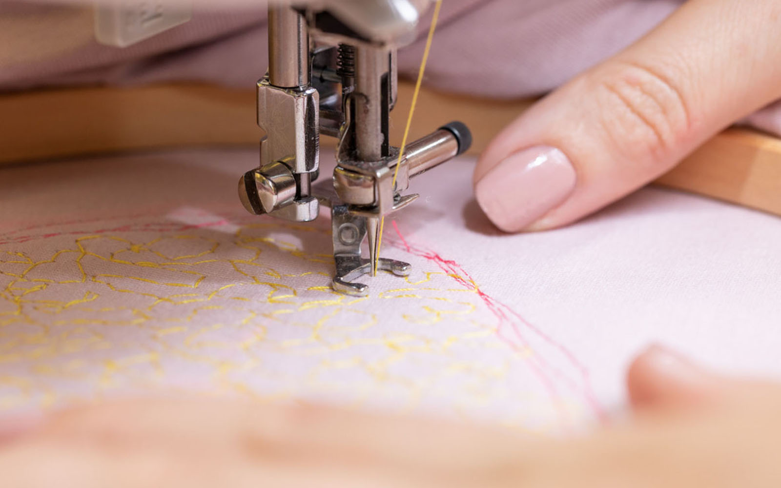 Hands holding wooden embroidery hoop stitching on sewing machine
