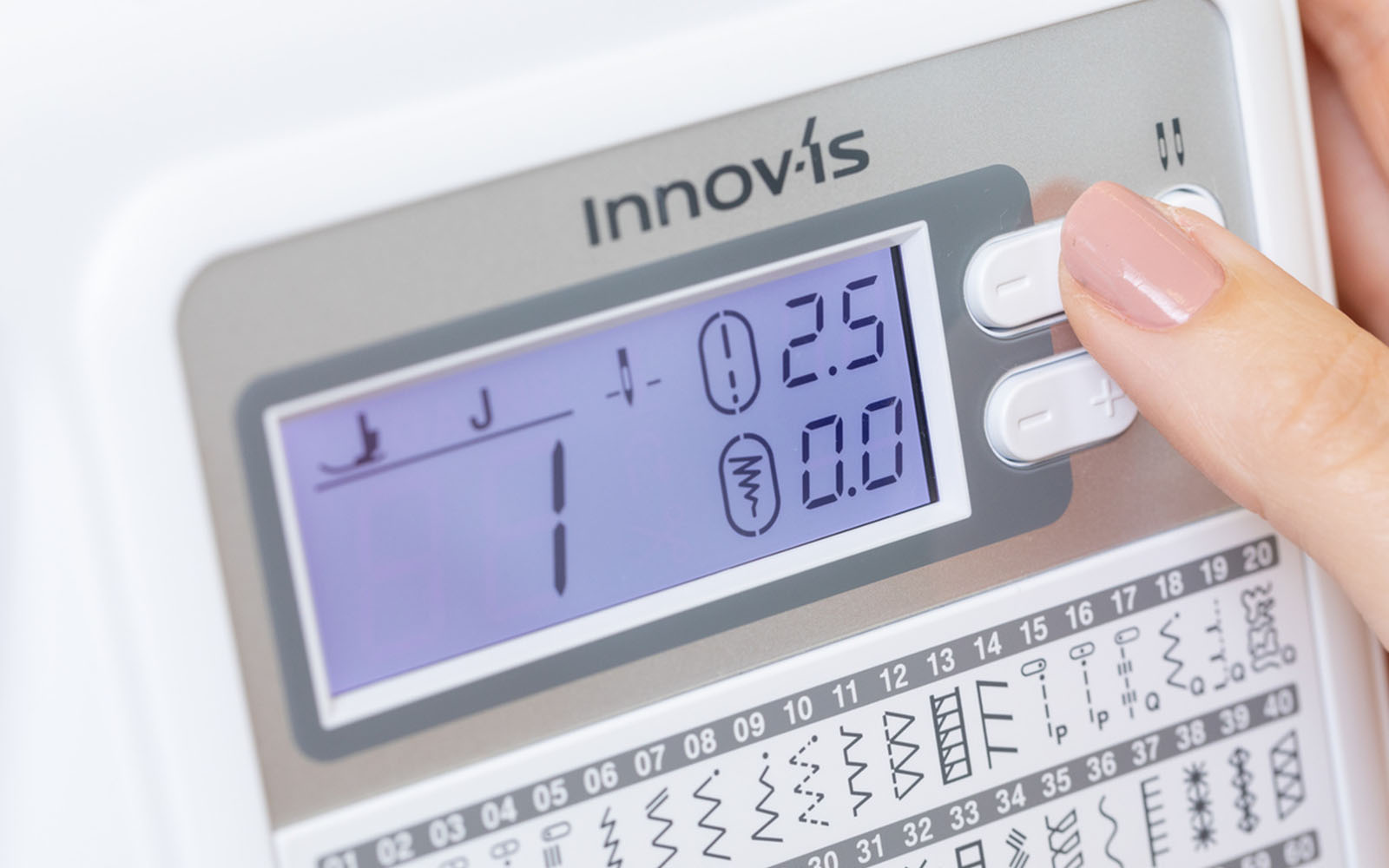 Thumb on stitch length button on sewing machine LCD screen