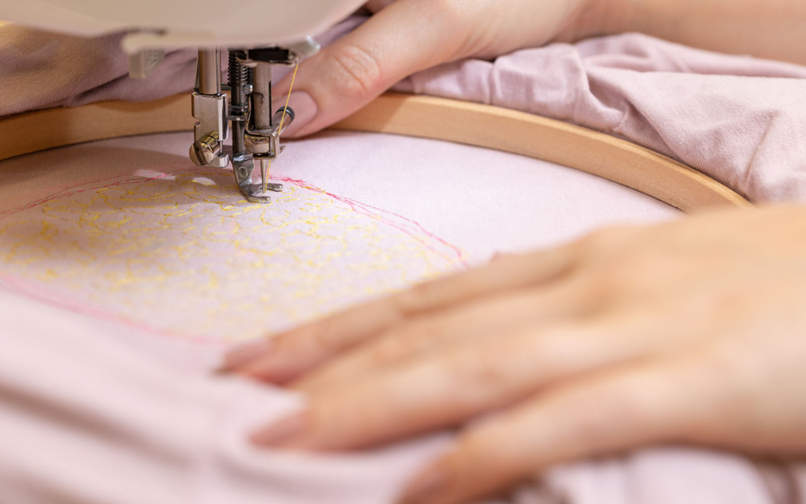 Mains tenant un cerceau de broderie en bois sur une machine à coudre