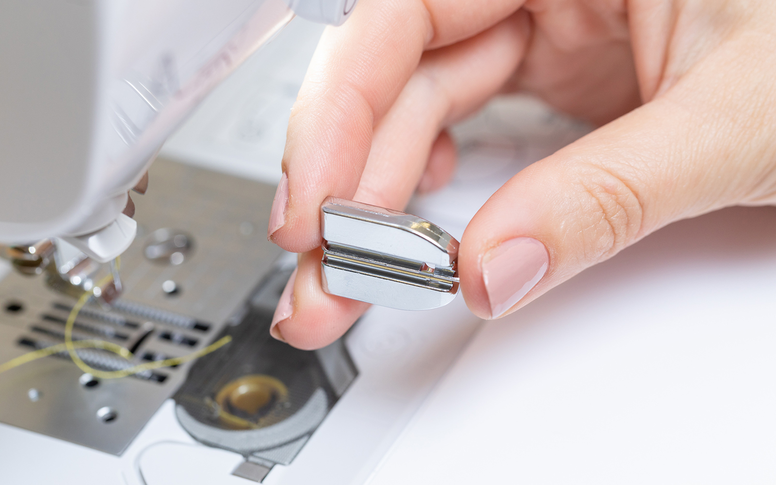 Hands holding up invisible zipper sewing machine foot