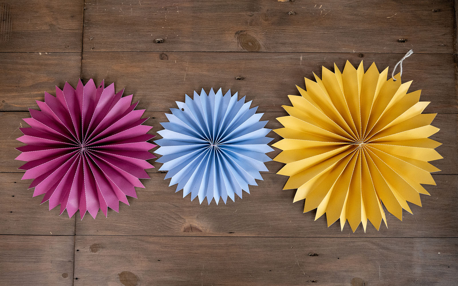 Pink, light blue and yellow paper star on wooden desk