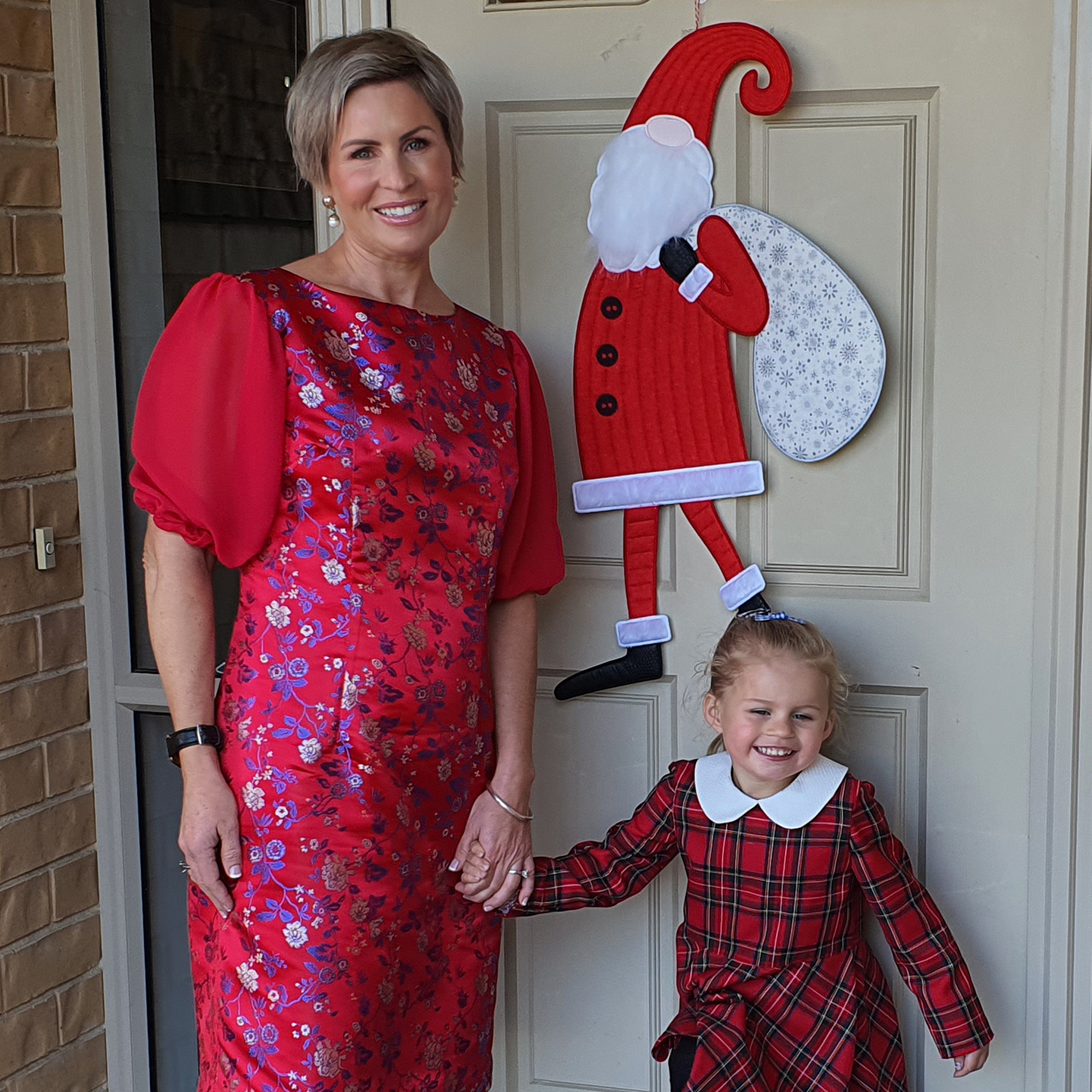 woman and girl standing in front of embroidered santa