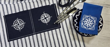 Blue apron and royal blue napkin with white nautical compass designs cut from heat transfer vinyl with Brother ScanNCut machine