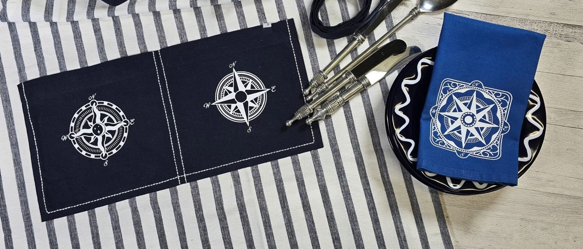 Tablier bleu et serviette de table bleu royal avec motifs de  boussoles nautiques blancs découpés dans du vinyle thermocollant avec la machine ScanNCut de Brother. 