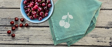 Machine embroidered cherry silhouette on green napkin