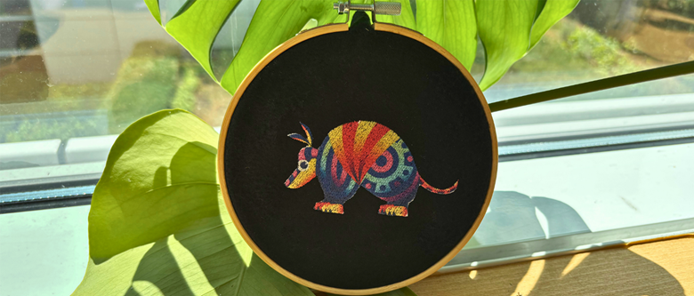 Colourful armadillo embroidered on black fabric
