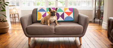 Geometrische Steppdecke in Primärfarben auf grauem Sofa