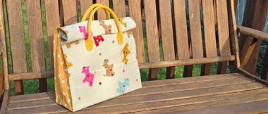 Cream roll up tote bag with dog pattern on bench