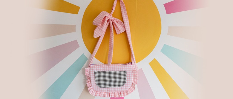 Handmade pink and black gingham bag against pastel sun burst