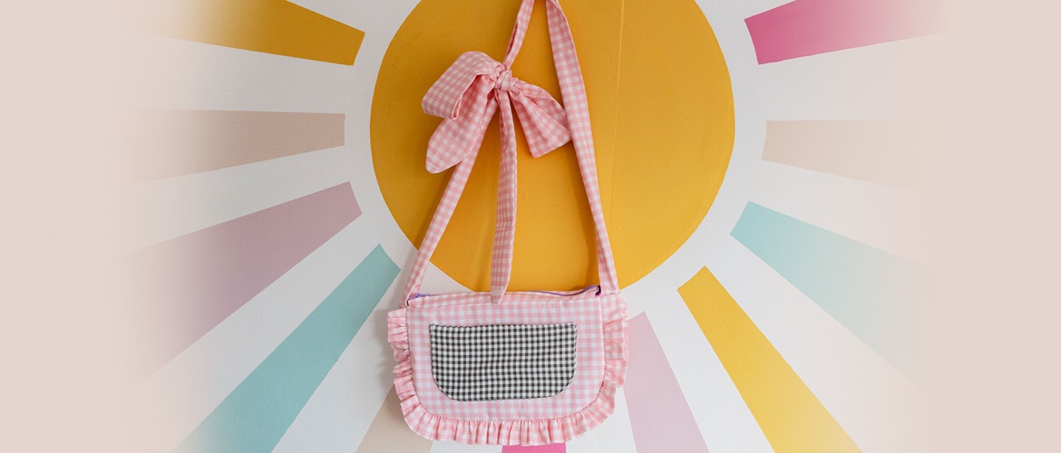 Handmade pink and black gingham bag against pastel sun burst