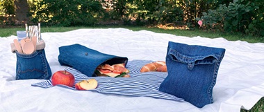 white picnic blanket with three denim lunch bags and apple